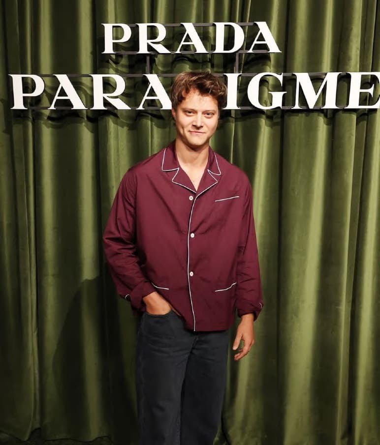 A JEM client in a burgundy pajama suit in front of the Prada Paradigme backdrop